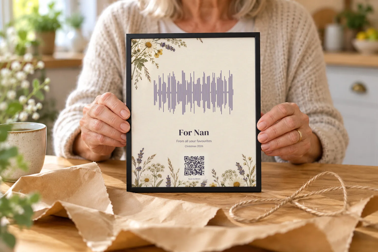 Hands holding a framed voice print for Nan, just unwrapped from brown paper
